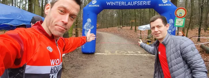 Zwei Mitglieder des RWO Endurance Teams stehen bereit für die Winterlaufserie in Hilden, mit dem Startbogen im Hintergrund.